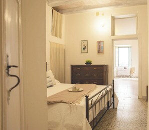 A bedroom with a bed, dresser, and a view of the outside. - Suite Porto antico - Alghero (Alghero)