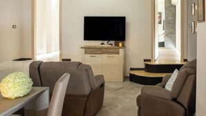 Un salon moderne avec un téléviseur à écran plat, deux canapés, une petite table et un meuble en bois.
