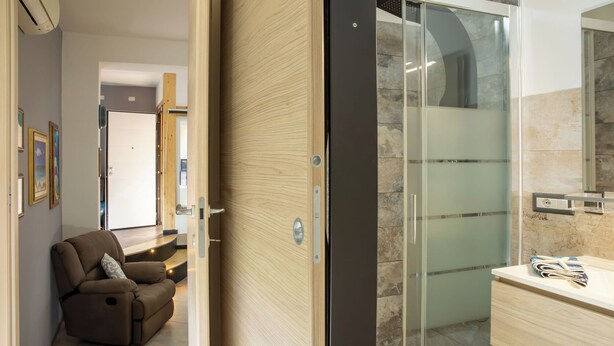 Une salle de bain moderne avec une douche à parois de verre, un meuble-lavabo en bois et un fauteuil inclinable.