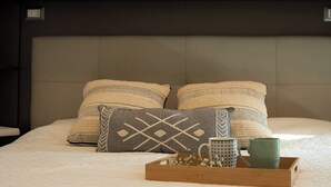 Un lit avec deux oreillers, un plateau avec deux tasses et une petite boîte de fleurs.
