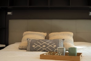 Ein Bett mit zwei Kissen, ein Tablett mit zwei Tassen und eine kleine Schachtel mit Blumen.