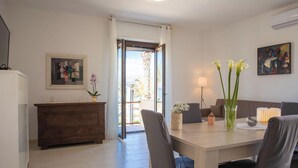 Een eetruimte met een houten tafel, stoelen, een vaas met bloemen, een lamp en een schilderij aan de muur.