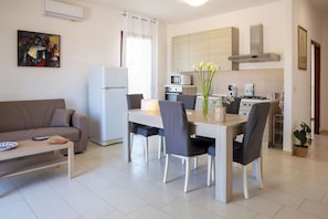 A modern kitchen with a dining area, a refrigerator, and a microwave. - Stella Maris - Alghero (Alghero)