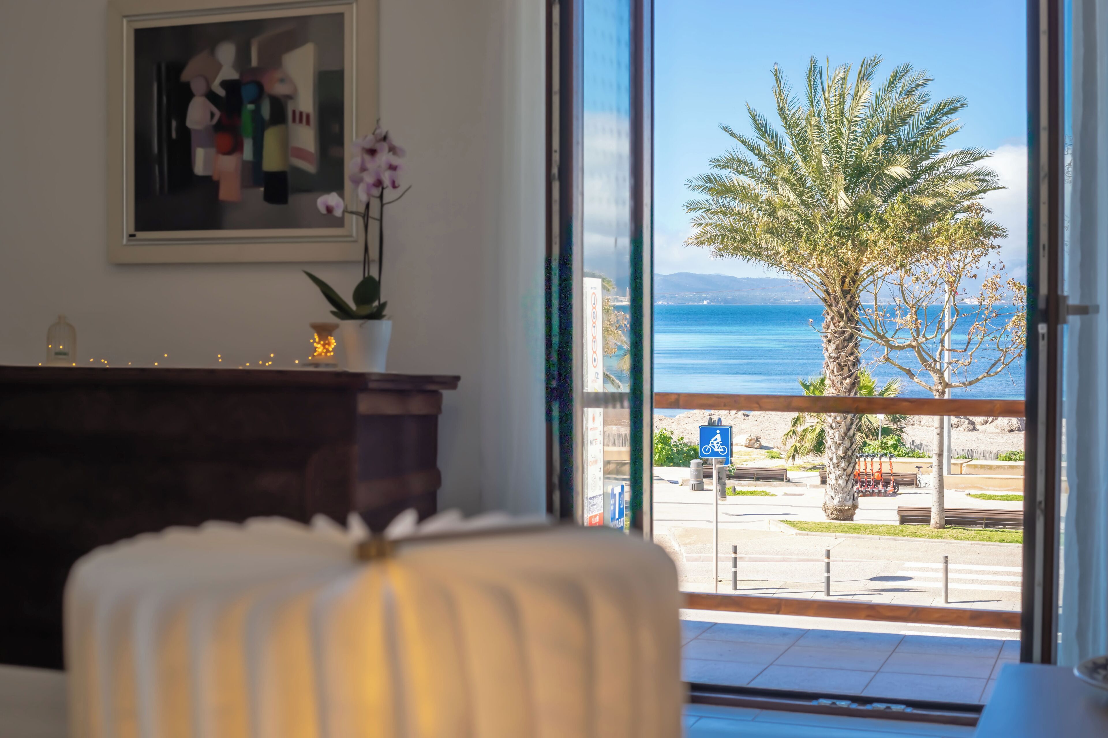 Una habitación con vista al mar, una planta en maceta y una obra de arte enmarcada en la pared.
