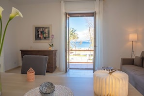A room with a desk, a chair, a sofa, a lamp, and a view of the sea through an open door. - Stella Maris - Alghero (Alghero)