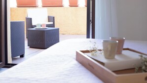 Een hotelkamer met een bed, een klein tafeltje met dienblad en een zithoek met stoelen en een tafel buiten.