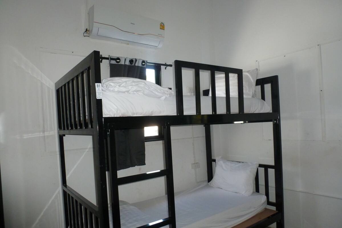 A bunk bed with a mattress, pillows, and a headboard.