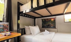 A bunk bed room with a painting, a table with snacks, and a sign listing services. - Nok Guest House And Hostel (Koh Tao)