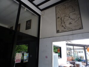 A map of Thailand, a door with a sign, and a window with a view of greenery. - Nok Guest House And Hostel (Koh Tao)