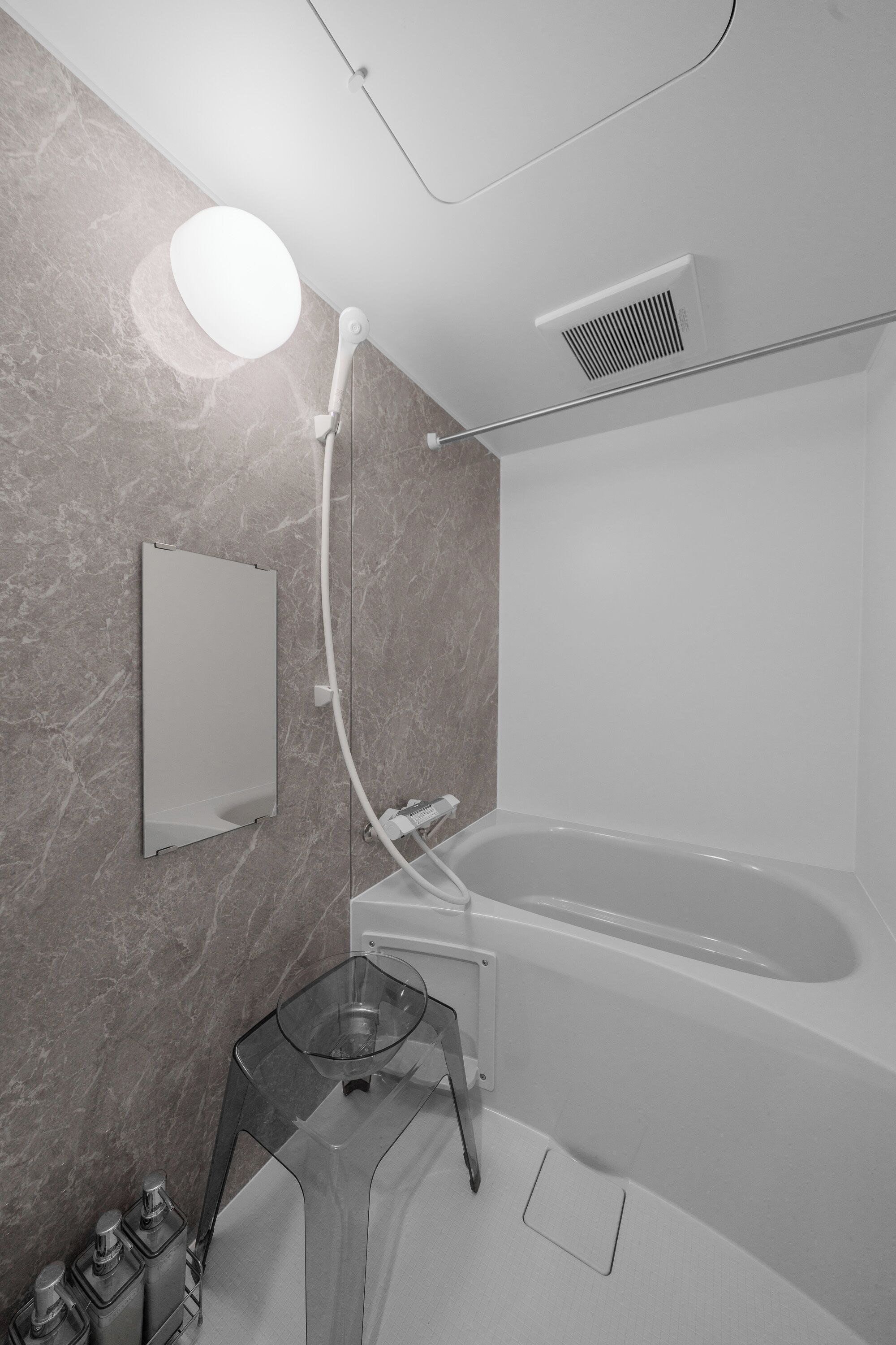 Een moderne badkamer met een bad, een glazen douchecabine en een marmeren wand.