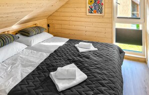 Una stanza con un letto, cuscini, una coperta trapuntata, un quadro e una finestra.