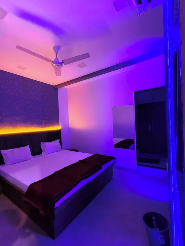 Une chambre Ă coucher moderne avec un lit, un ventilateur de plafond et un grand miroir.