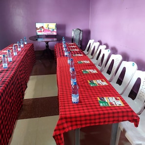 A conference room with a long table, chairs, water bottles, and a television screen.