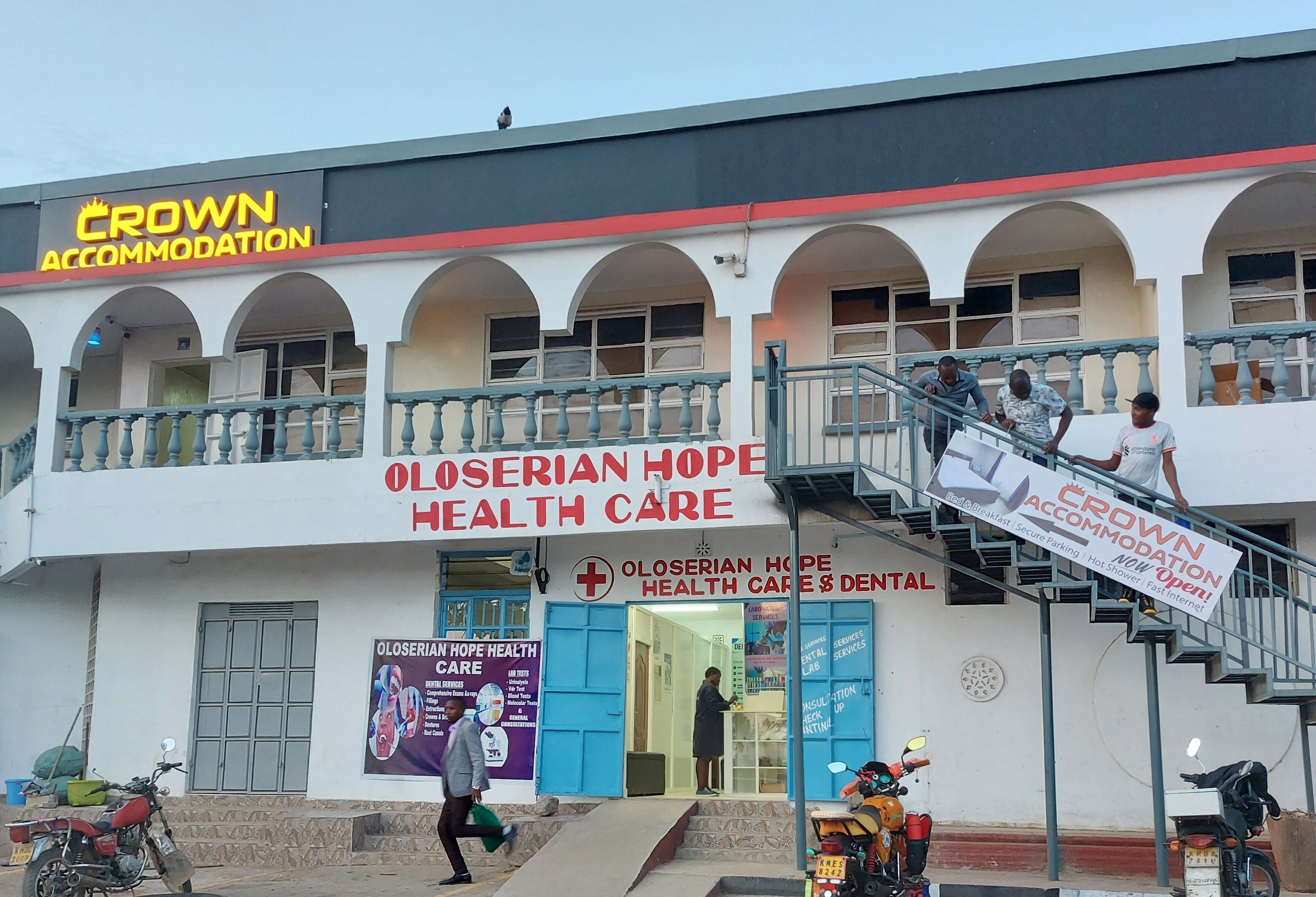 A building with a sign for 'Crown Accommodation' and 'Oloserian Hope Health Care & Dental'.