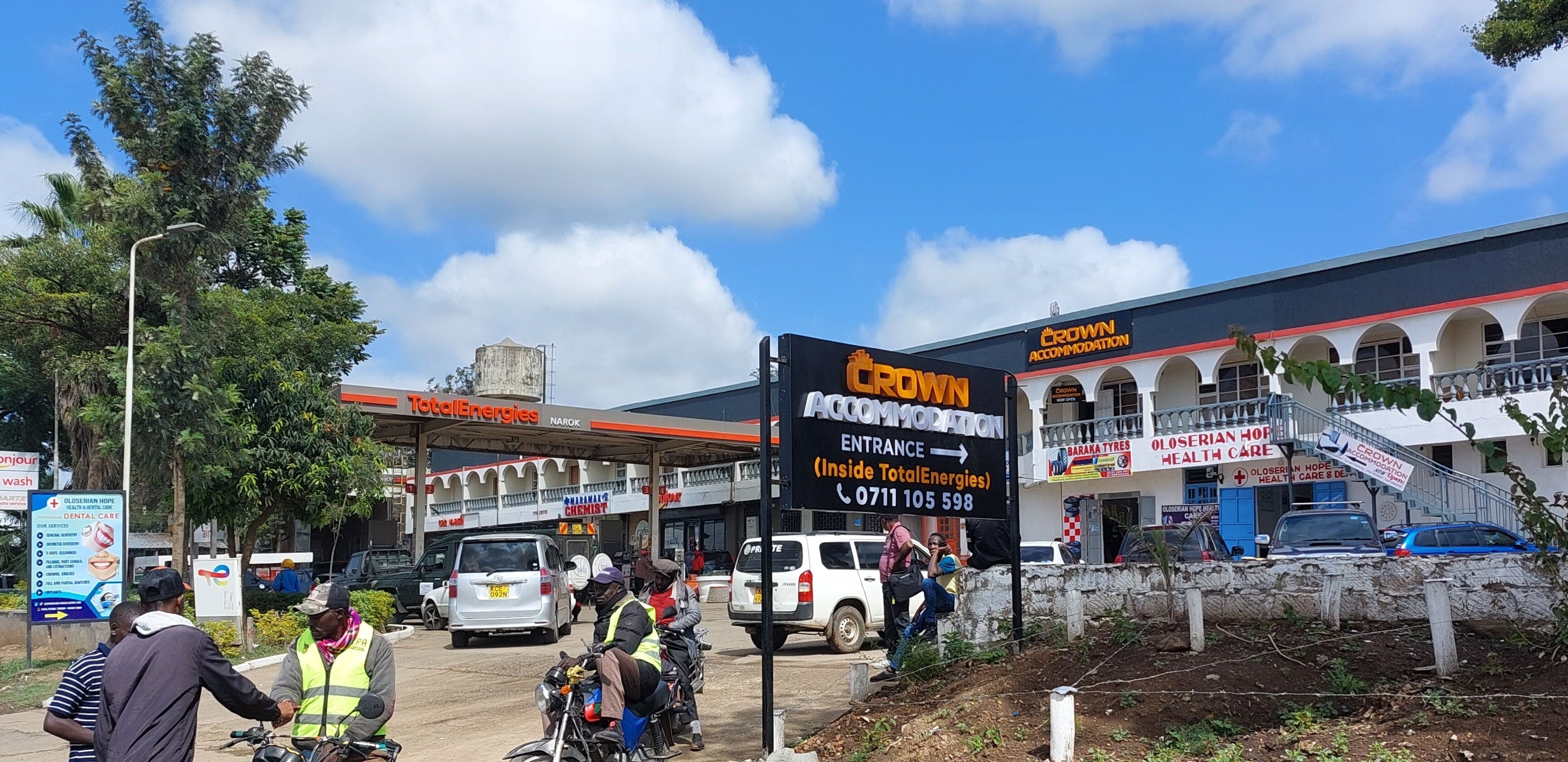 Un immeuble avec une enseigne indiquant « Crown Accommodation » et une station-service TotalEnergies.