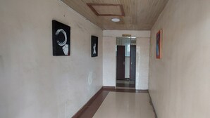 A hallway with a reception area, framed artwork on the walls, and a tiled floor. - Crown Accomodation (Narok)