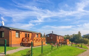 A row of wooden cabins with a fenced yard, satellite dishes, and a clear sky. - Awesome home in Radkow with WiFi (Radkow)