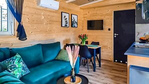 A cozy room with a sofa, a dining table with chairs, a small kitchen area, and a door. - Awesome home in Radkow with WiFi (Radkow)