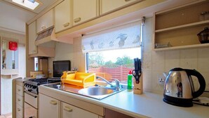 Une cuisine équipée d’une cuisinière, d’un évier et de divers ustensiles.
