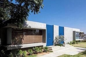 A modern house with a blue door, a large window with blinds, and a well-maintained lawn. - JAVA RAIN RESORTS (Chikkamagaluru)