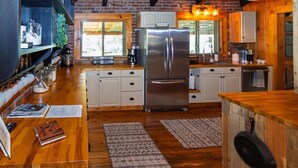 Una cocina con armarios de madera, un refrigerador de acero inoxidable y una pared de ladrillo.