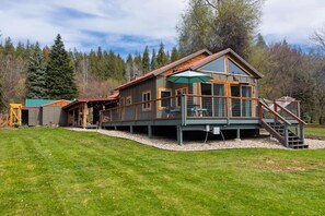 A two-story cabin with a deck, large windows, and a staircase leading to the upper level.