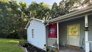 Una casa azul claro con porche, una bandera roja y un jardín lleno de girasoles.