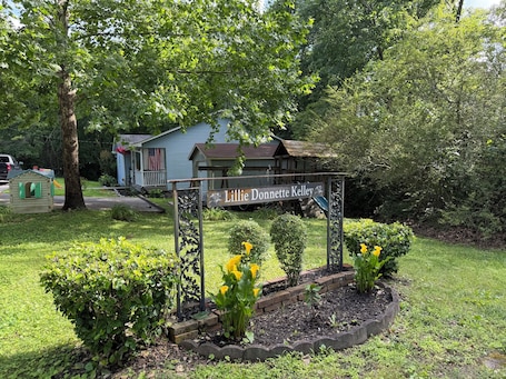 A sign with the name 'Lillie Donnett Kelley' in a garden area with a house in the background.. 3-bed/1-bath Home in charming Pegram - TriStar Tribe Country Cottage