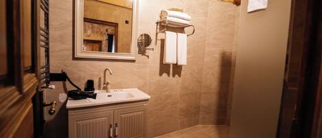 Un baño con lavamanos, espejo, toallero y zona de ducha.