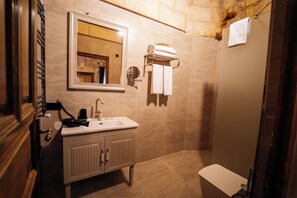 A bathroom with a sink, mirror, towel rack, and shower area.