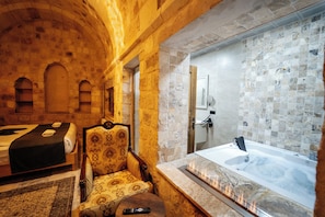 A room with a bed, a chair, a fireplace, and a bathtub.