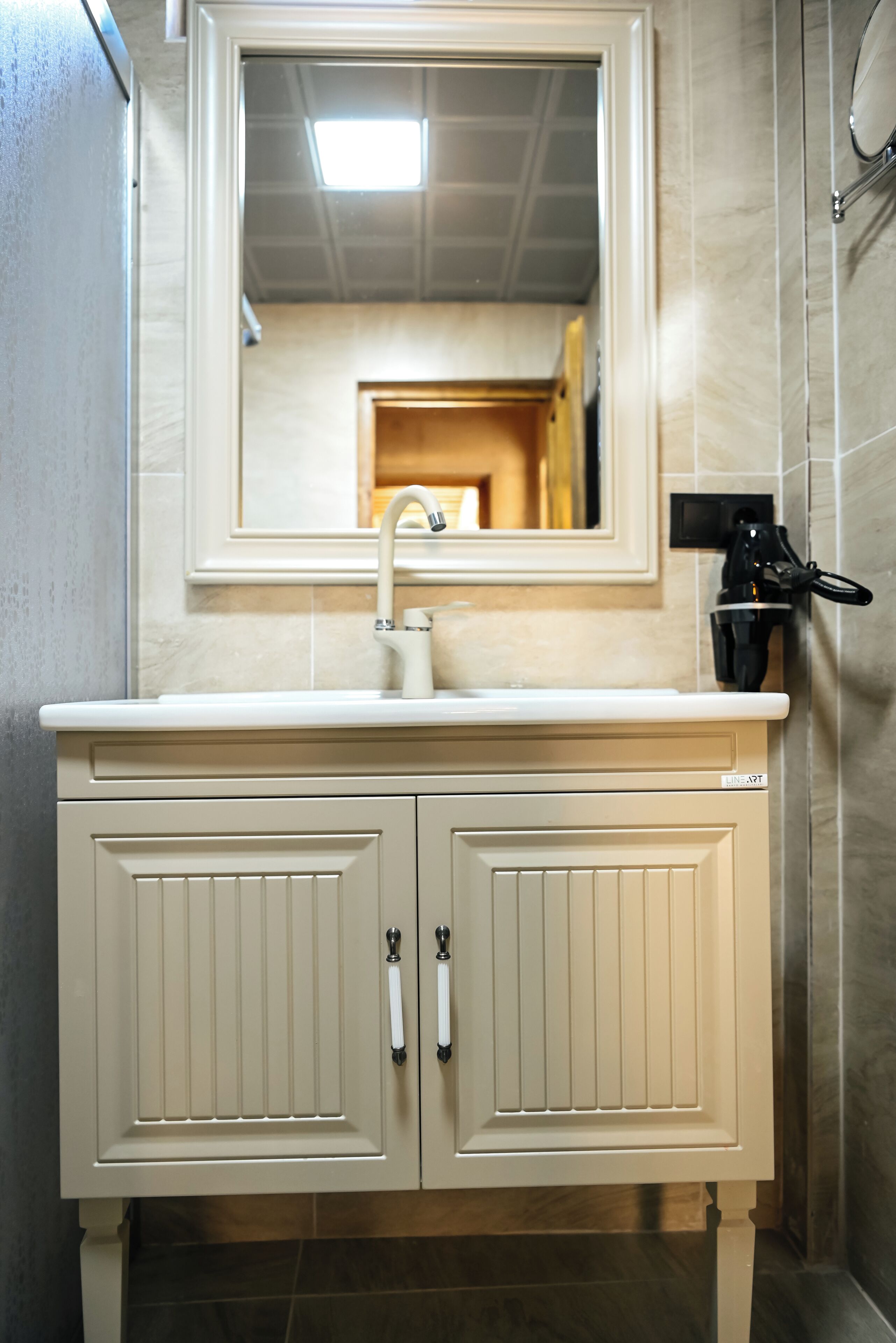 A bathroom with a white vanity, a mirror, a sink, and a towel rack.