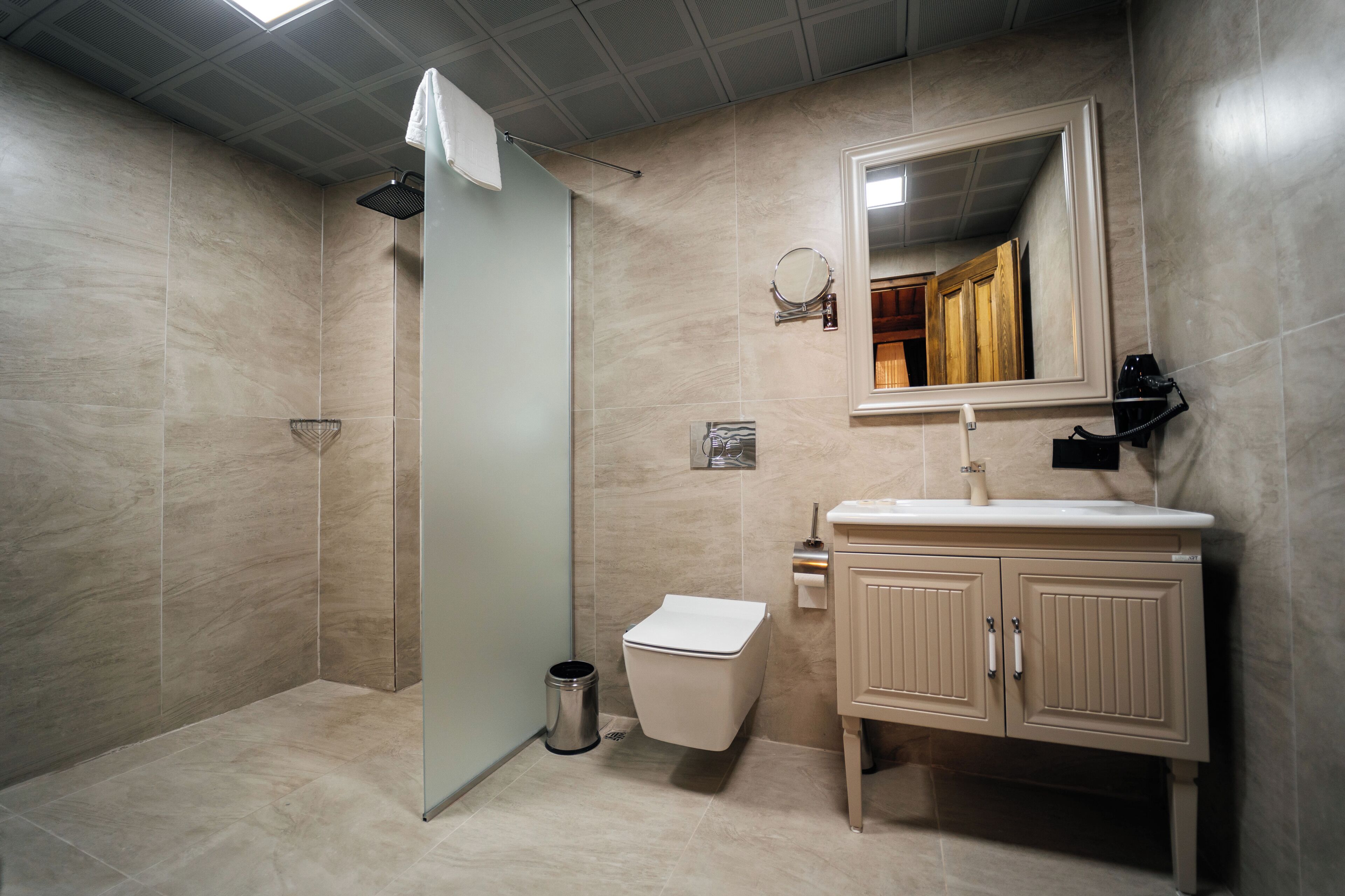 Een badkamer met douche, toilet, wastafel en spiegel.