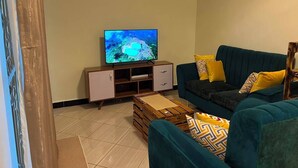 A living room with a TV, a sofa, a coffee table, and a cabinet. - Amala Homes – Private Stay in Mukono (Mukono)