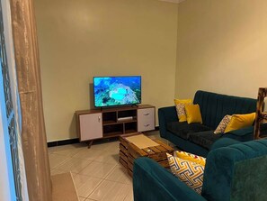 Ein Wohnzimmer mit Fernseher, einer Couch, einem Couchtisch und einem Schrank.
