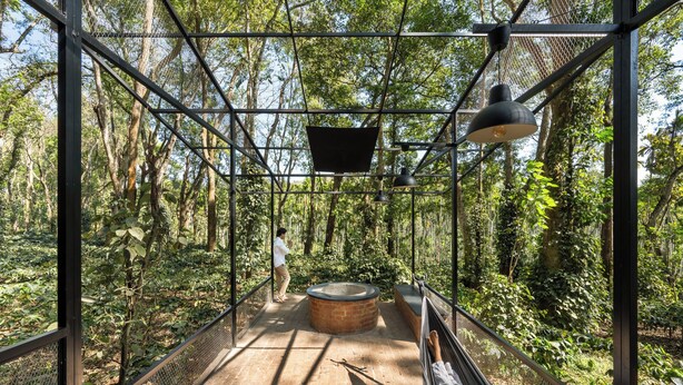 A hammock chair, a round brick fire pit, and a metal mesh structure in a forested area. - Container cabin retreat on a 70-acre Coorg estate with estate views (Siddapur)