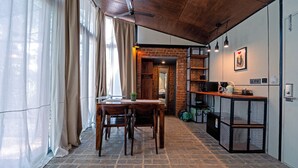 A dining area with a brick wall, wooden table, and chairs. - Container cabin retreat on a 70-acre Coorg estate with estate views (Siddapur)