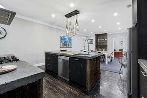 A modern kitchen with a central island, stainless steel appliances, and a hanging light fixture.