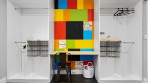 Uma lavanderia com parede colorida, uma cadeira e duas cestas de arame.