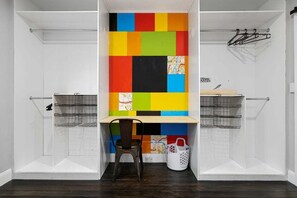 A laundry room with a colorful wall, a chair, and two wire baskets.