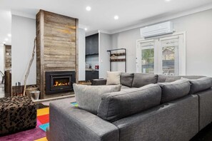 A modern living room with a fireplace, grey sofa, and a colorful rug.