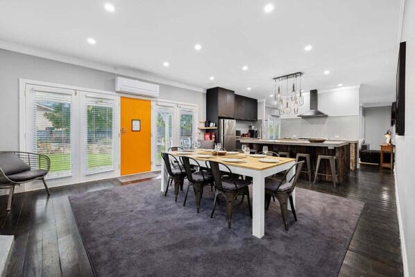 A modern kitchen with a dining area, large windows, and a view of the outdoors. - Edelweiss Cottage - Serene and spacious Berridale Accommodation (Berridale)
