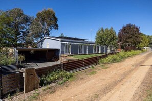A single-story building with a garage, surrounded by a fence and trees. - Edelweiss Cottage - Serene and spacious Berridale Accommodation (Berridale)