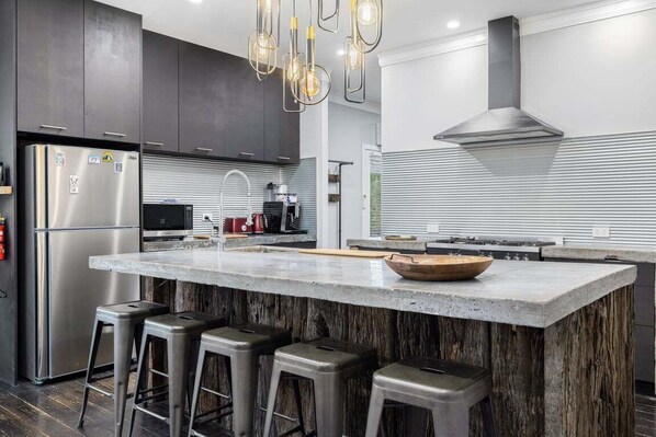 A modern kitchen with a large island, stainless steel appliances, and bar stools.