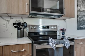 A kitchen with a stainless steel oven, a microwave, and wooden cabinets. - Modern Home Near Old Mill & River (Bend)