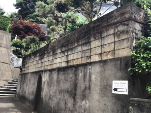 A concrete wall with a sign indicating a direction to Minsyuku Chatamago. - Chatamago (Nagasaki)