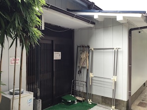 A room with a door, a small green mat, a metal rack, and a sign on the wall. - Chatamago (Nagasaki)