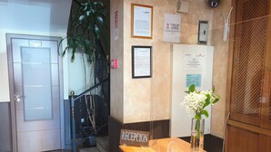 A reception area with a wooden counter, a reception sign, and a staircase with a plant. - Hostal Avenida Barajas (Madrid)
