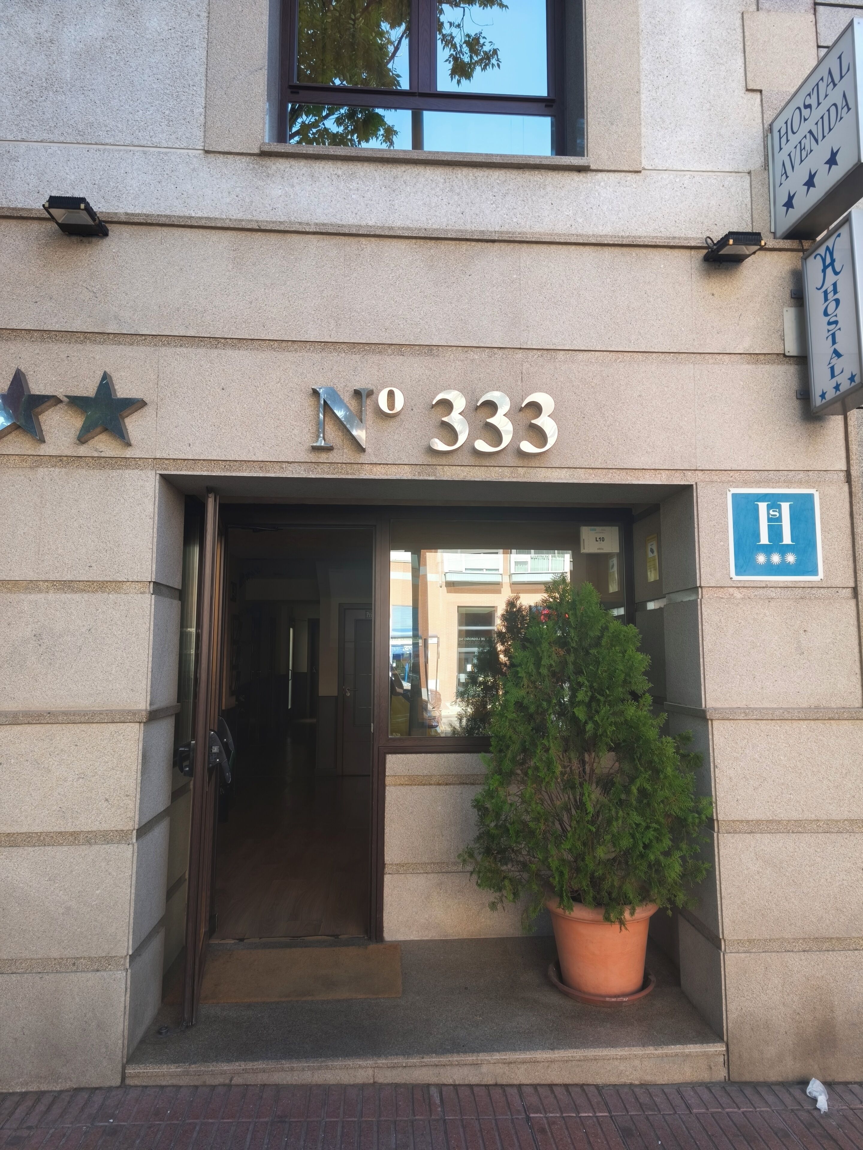A building entrance with a sign reading 'No 333' and a potted plant outside.