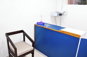 A reception desk with a blue partition, a wooden chair, and a bottle of water. - Hotel Yub-Raj Near Puri Beach  (Puri)